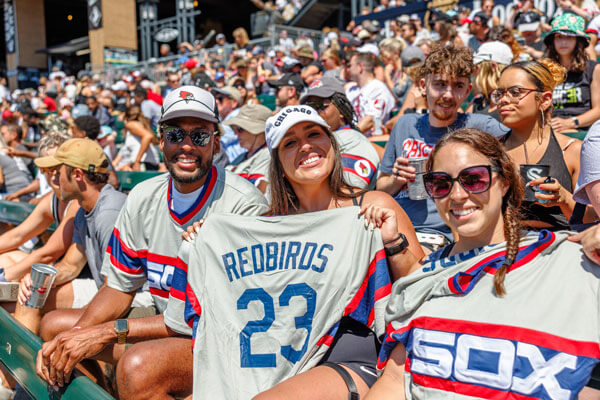 Three Redbird alumni hold up Sox jerseys with Redbird written across the back.