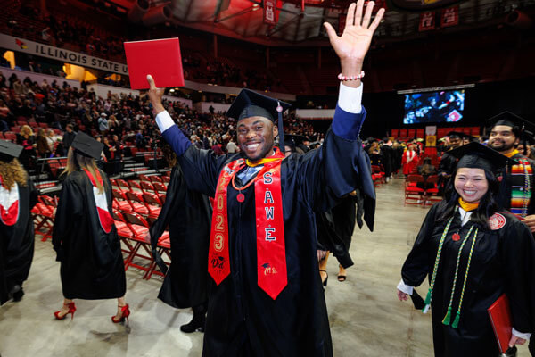 A graduate with a diploma in his hand celebrates during commencement.