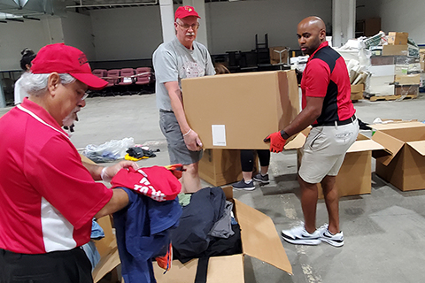 three men moving boxes of clothes in warehouse