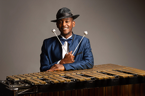 man holding vibraphone mallets and standing behind vibraphone